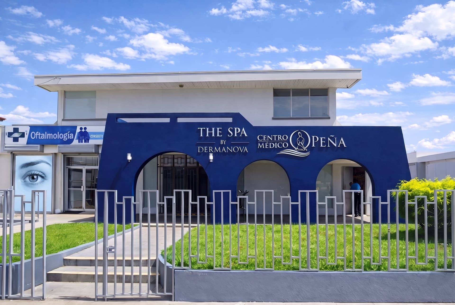Fachada del edificio de Clínica Peña Alfaro en Alajuela: a la izquierda, el rótulo de Oftalmología; al centro, la fachada azul con tres arcos.