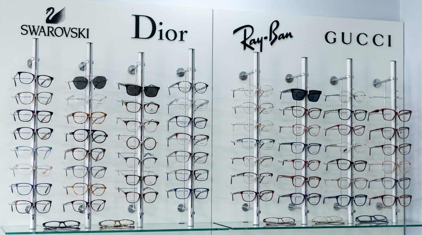 Pared de aros de la óptica, con anteojos y lentes de sol bajo los rótulos de Swarovski, Dior, Ray-Ban y Gucci